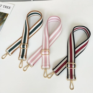 Macro detail of adjustable bohemian striped canvas bag straps with gold metal hooks