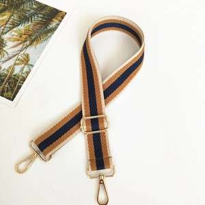 Detail of adjustable brown and navy striped fabric shoulder strap with gold metal buckles