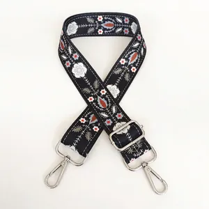 Detail of floral embroidery on wide crossbody strap with silver lobster clasps