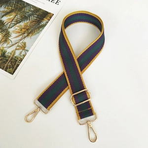 Detail of adjustable woven bag strap with purple, green, and yellow stripes and gold hooks