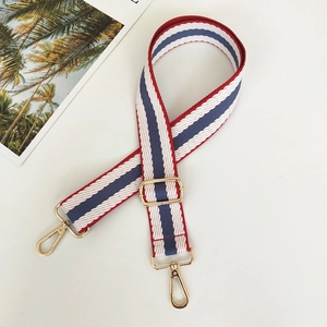 Detail of adjustable canvas bag strap with red, white, and blue stripes and gold hooks