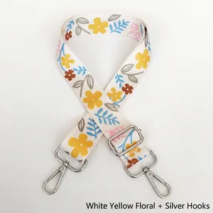 Detail of adjustable white floral bag strap with colorful patterns and silver metal hooks