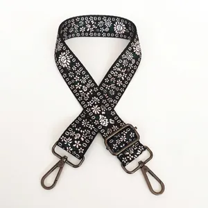 Detail of floral embroidery on adjustable black bag strap with gunmetal swivel hooks