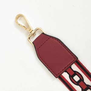Detail of wide woven strap with golden lobster clasp and premium burgundy leather joints