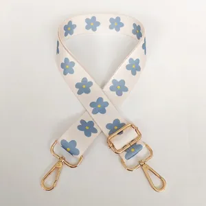 Close-up of adjustable beige floral strap with blue flowers and gold metal hooks