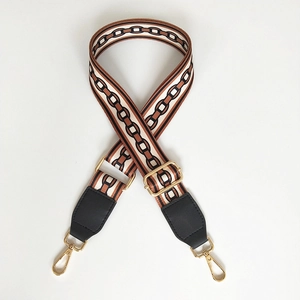 Macro view of adjustable wide fabric bag strap with retro geometric patterns and gold clips