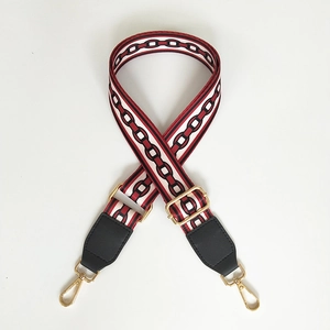 Close-up of red and black chain pattern woven bag strap with golden metal carabiners