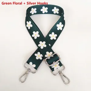 Detail of adjustable green floral guitar strap with silver hooks and daisy patterns