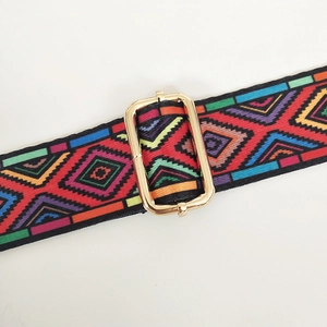 Macro view of woven canvas strap featuring ethnic patterns and golden metal adjustment buckle