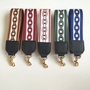 Detail of wide knitted replacement bag straps with geometric chain patterns and gold hooks