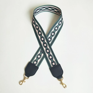 Detail of colorful woven bag strap with geometric patterns and gold metal swivel hooks