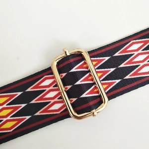 Close-up of ethnic geometric pattern woven bag strap with golden metal buckle detail