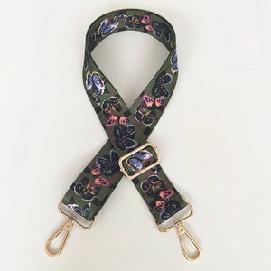 Detail of adjustable wide canvas bag strap with colorful butterfly print and gold hardware