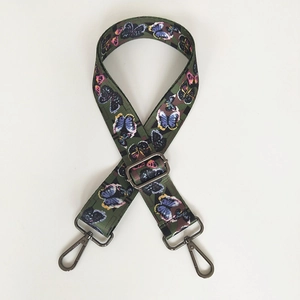 Close-up of olive green canvas bag strap with colorful butterfly prints and metal hooks