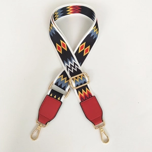 Detail of adjustable ethnic geometric pattern bag strap with red leather and gold lobster clasp