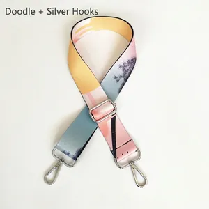 Detail of adjustable woven bag strap featuring colorful graffiti patterns and silver metal clips