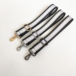 Close-up of adjustable striped bag straps with silver thread and metallic lobster clasps