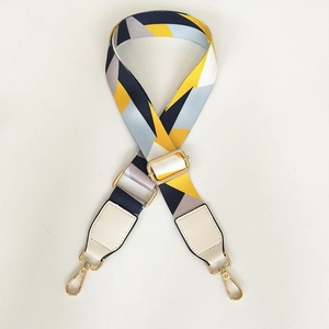 Detail view of adjustable wide bag strap with colorful geometric pattern and gold hardware