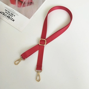 Detail of red nylon strap with gold metal lobster clasp and adjustable buckle on white surface