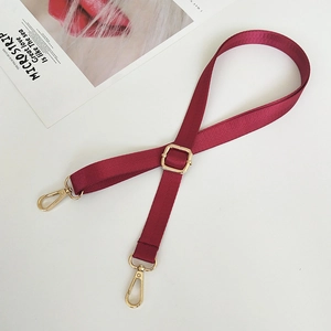 Detail showing burgundy nylon bag strap with gold metal hooks and adjustable buckle