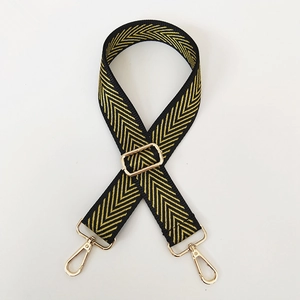 Detail of adjustable black and yellow chevron embroidery bag strap with gold metal hooks