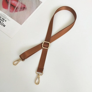 Close-up of brown nylon bag strap with golden lobster clasps and metal adjustment ring