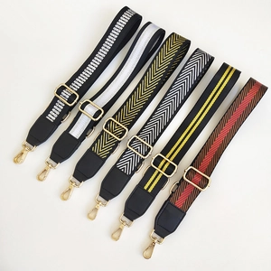 Detail view of adjustable wide woven bag straps with geometric patterns and gold buckles