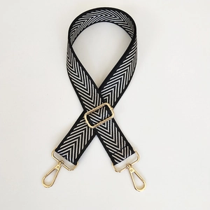 Detail of adjustable black and white herringbone bag strap with polished gold hardware