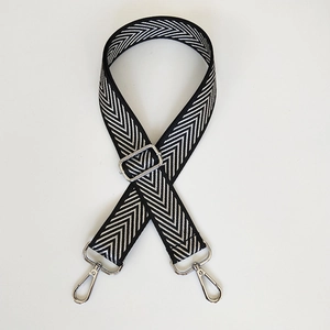 Detail of adjustable black and white herringbone shoulder strap with silver metal swivel hooks