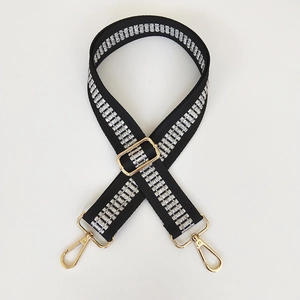 Detail showing the black woven shoulder strap with silver patterns and gold lobster clasps