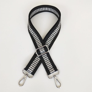 Detail of adjustable black embroidered bag strap with silver geometric glitter patterns