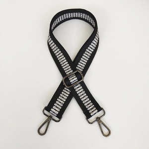 Detail of adjustable black bag strap with silver embroidery and metal lobster clasps