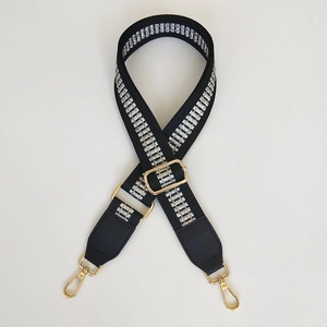 Close-up of black bag strap with silver ladder weave pattern and gold hardware hooks