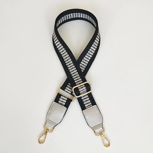 Detail of black and silver woven adjustable shoulder strap with golden metal lobster clasps