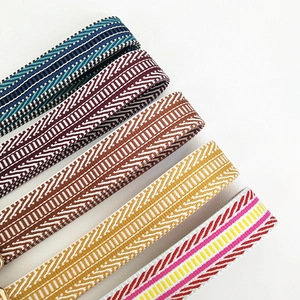 Detail view of five wide embroidered bag straps with ethnic patterns and metal buckles