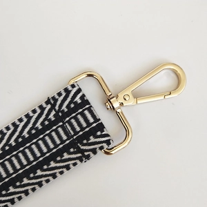 Detailed view of geometric black and white woven strap with light gold lobster clasp hardware