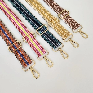 Close-up of five colorful embroidered woven bag straps with gold metal hooks and buckles