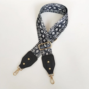 Detail of adjustable snakeskin canvas bag strap with golden hardware and leather ends