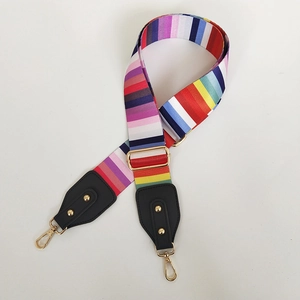Detail of rainbow striped canvas bag strap with golden lobster clasps and black leather trim