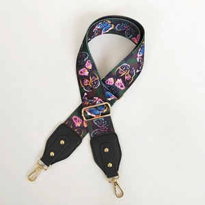 Detail of wide nylon crossbody strap with colorful butterfly print and gold metal hooks