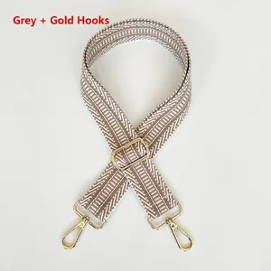 Detail view of wide gray geometric woven bag strap with adjustable gold hardware buckles