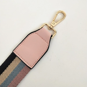 Detail van de gestreepte tasriem met roze PU-leer en een gouden metalen karabijnhaak