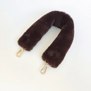 Detail of soft dark brown faux rabbit fur bag strap with golden metal lobster clasps