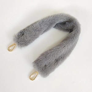 Close-up of fluffy grey faux fur bag strap with polished gold lobster clasps and soft texture