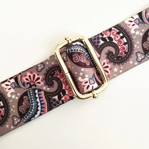 Detail of adjustable golden metal buckle and paisley pattern ethnic wide strap