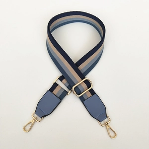Detail van verstelbare brede schouderriem met blauwe en beige strepen en gouden haken