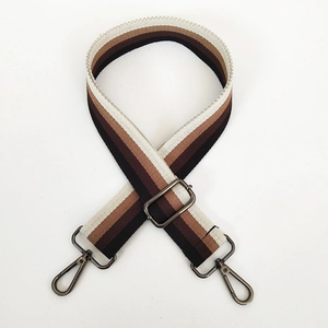 Detail of adjustable wide woven bag strap with brown and beige stripes and metal buckles