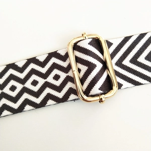 Detail of black and white wave pattern woven bag strap with golden metal buckle