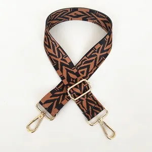 Close-up of ethnic geometric pattern wide bag strap with gold metal hooks and buckle