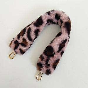 Macro view of plush leopard print faux fur bag strap with golden metal swivel hooks